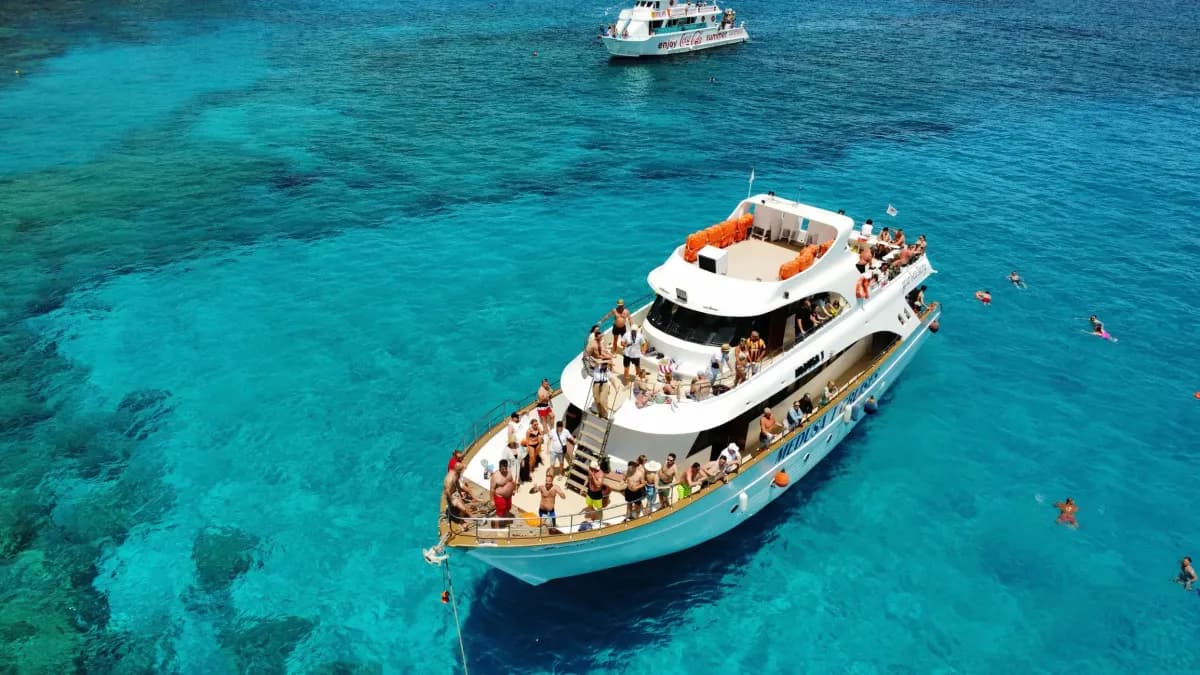 Passengers aboard a large excursion boat while others swim nearby